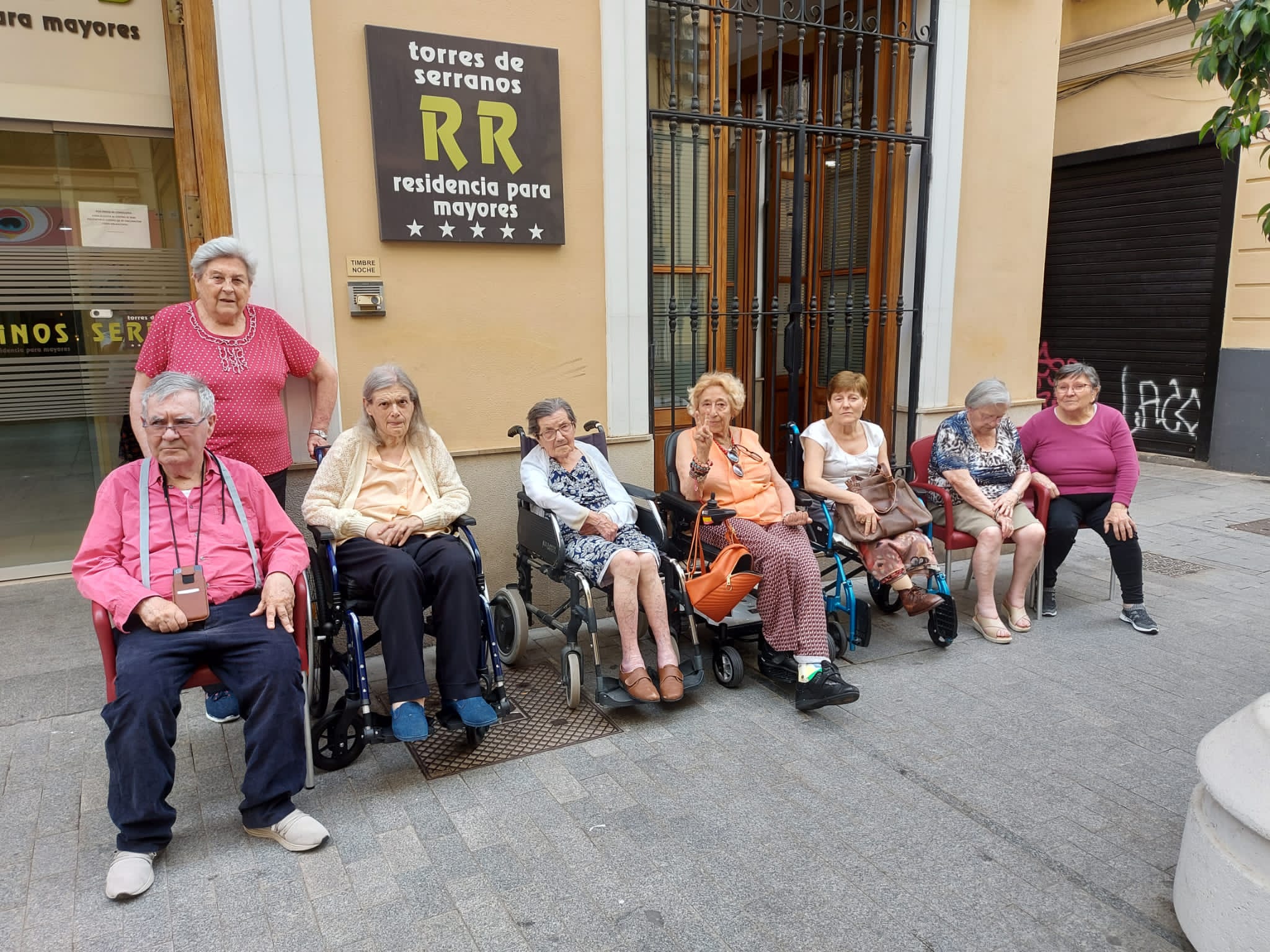 Grupo de persona mayores sentadas en las afueras de la residencia